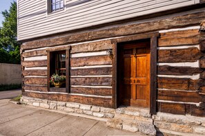 Une cabane en rondins avec une porte et une fenêtre en bois, le numéro 318 étant visible sur la porte.
