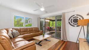 Un salon avec un canapé en cuir marron, une table basse en bois et un ventilateur de plafond.