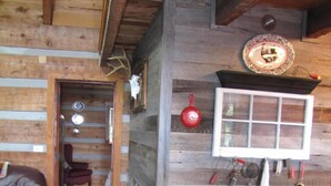 Un interior rústico con paredes de madera, suelo de baldosas de piedra y una chimenea con un ventanal encima.