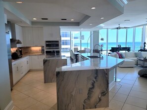 A modern kitchen with a marble island, built-in oven, and large windows overlooking the ocean. - Seabliss ~Gulf Front, Luxury~ Walls of Windows!! (DESTIN)