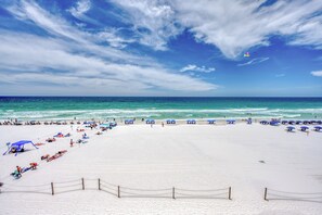 Una playa con cielo despejado, océano y gente disfrutando del sol.