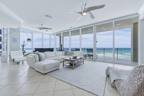 A spacious living room with a large white sectional sofa, a coffee table, and a view of the ocean through floor-to-ceiling windows. - Seabliss ~Gulf Front, Luxury~ Walls of Windows!! (DESTIN)
