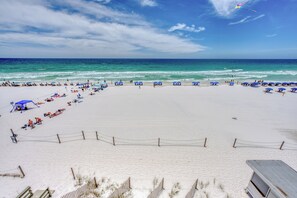 A beach with a fenced area, beach umbrellas, and people sunbathing. - Seabliss ~Gulf Front, Luxury~ Walls of Windows!! (DESTIN)