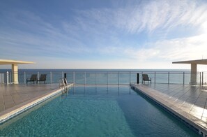 A clear blue sky, a swimming pool with a view of the sea, and two lounge areas with chairs. - Seabliss ~Gulf Front, Luxury~ Walls of Windows!! (DESTIN)