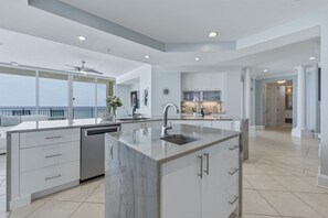 A modern kitchen with a central island, built-in appliances, and a view to the outside. - Seabliss ~Gulf Front, Luxury~ Walls of Windows!! (DESTIN)