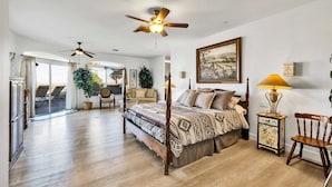 A spacious bedroom with a large bed, two ceiling fans, a bedside table with a lamp, and a view of the outdoors through a sliding glass door. - ** 4BR, Absolute Privacy, Jacuzzi, Pool Heating Can Be Added** (Palm Springs)