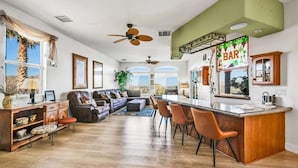 A spacious living area with a large sofa, a dining area with bar seating, and a kitchen with a bar counter. - ** 4BR, Absolute Privacy, Jacuzzi, Pool Heating Can Be Added** (Palm Springs)
