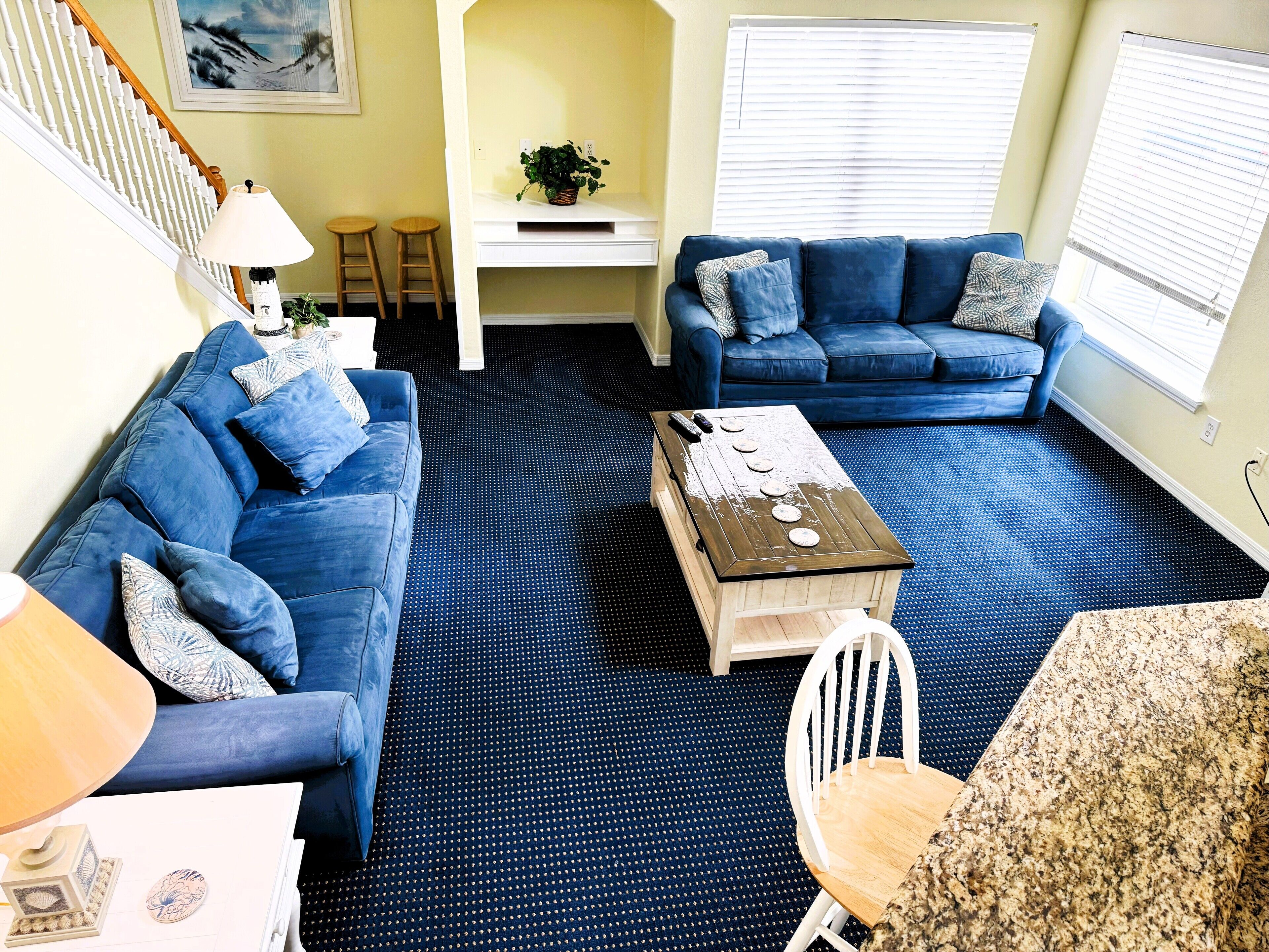 A living room with a blue sofa set, a coffee table, and a dining table with chairs.