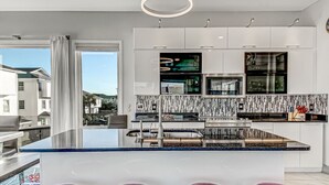 A modern kitchen with a central island, stainless steel appliances, and a view of the outside.