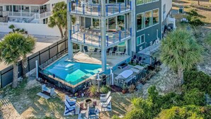 A multi-story building with a pool, outdoor seating, and a view of the surrounding area.