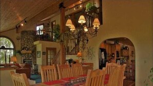 A dining area with a wooden table and chairs, a chandelier, and a view of the kitchen and upper level. - Private Home with Great Views & Hot Tub (Steamboat Springs)