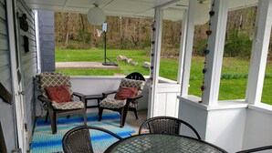 A covered patio with a glass table and chairs, a basketball hoop, and a view of a grassy yard. - In the ❤ of Ohiopyle. Central location, clean, charming. Large yard with firepit (Ohiopyle)