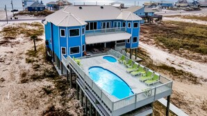 A beachfront house with a pool, multiple decks, and a view of the ocean.