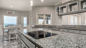 A modern kitchen with granite countertops, a built-in stove, and a view of the ocean.