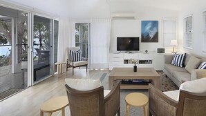 Una sala moderna con televisión de pantalla plana, un sofá y un comedor con sillas y una mesa de centro.