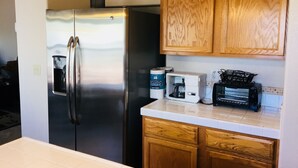 Une cuisine équipée d’un réfrigérateur en acier inoxydable, de meubles de rangement en bois, d’un four à micro-ondes et d’un grille-pain.