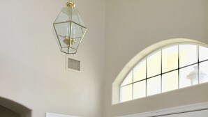 Une pièce avec deux portes blanches, une petite fenêtre à carreaux et un luminaire au plafond.