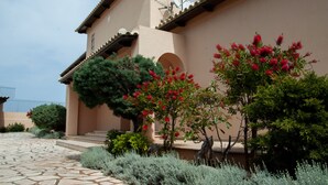 A building with a beige facade, a satellite dish, and a stone-paved entrance. - Villa Hera At Cape Sounion (Lavreotiki)