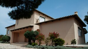 A two-story house with a tiled roof, a front porch, and a stone-paved entrance. - Villa Hera At Cape Sounion (Lavreotiki)