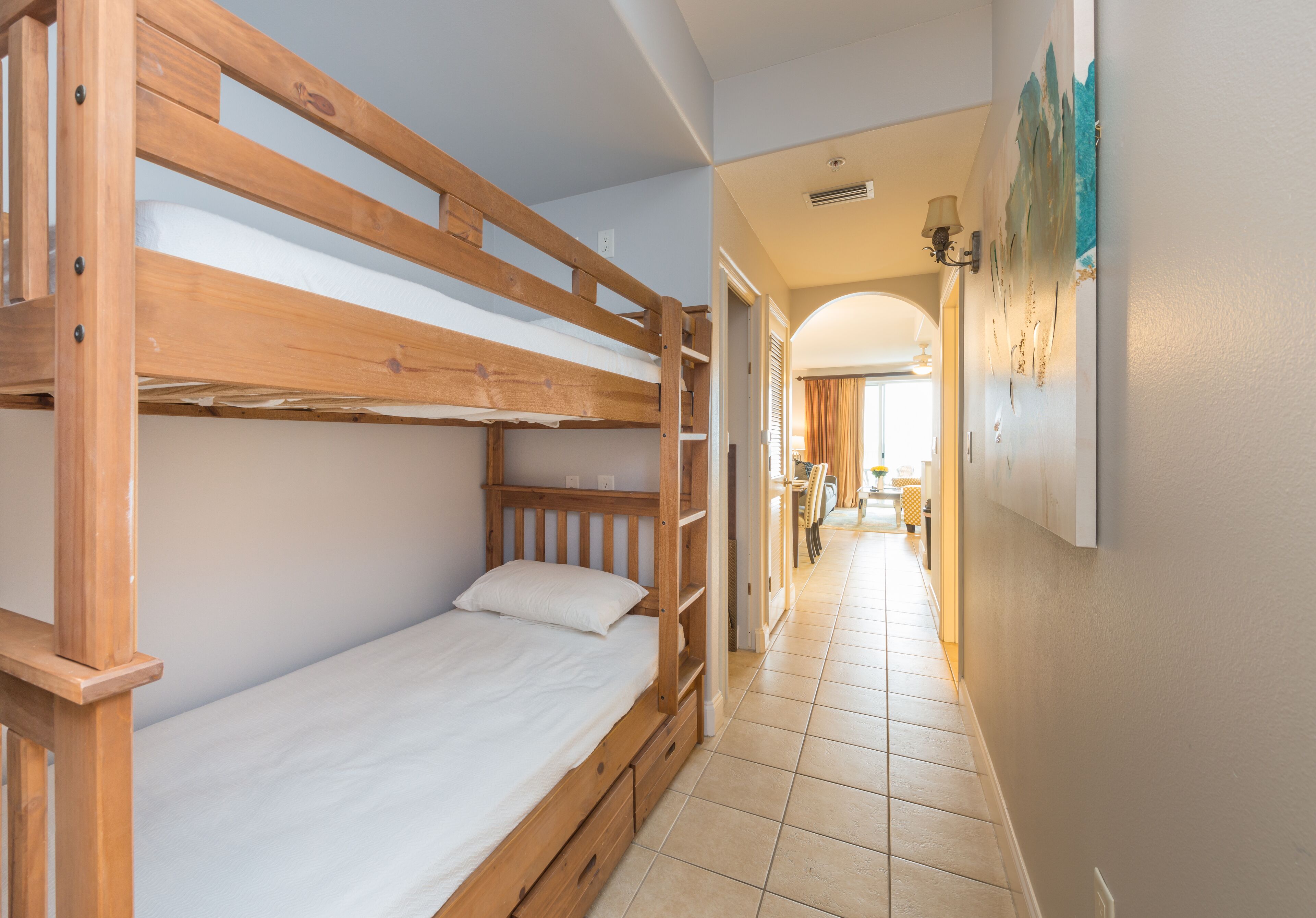 Een slaapkamer met stapelbedden en een gang die naar een eetgedeelte leidt.