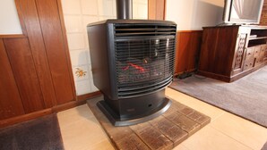 A wood-burning stove with a chimney, placed on a tiled floor with a rug. - Seagate Beach Retreat - with private pool and integrated spa (spa is unheated). (Rockingham)