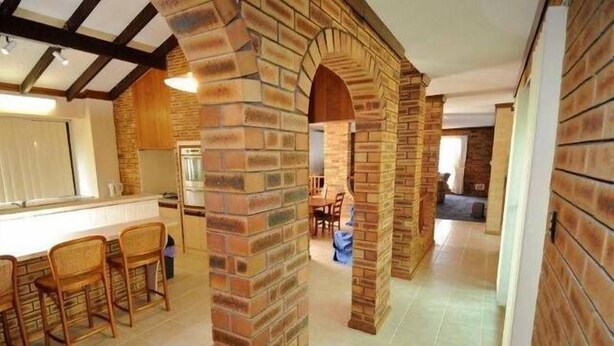 A spacious kitchen with brick arches, a dining area with wooden chairs, and a visible refrigerator. - Seagate Beach Retreat - with private pool and integrated spa (spa is unheated). (Rockingham)