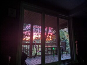 A room with a large window overlooking a wooden deck with chairs and a table. - River Views | Pool Table | EV Charger | Hiking Trails | Near Niagara Falls (St. Catharines)