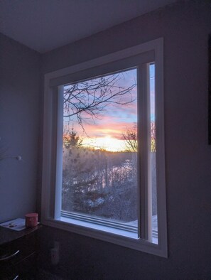 A window with a view of a sunset over a snowy landscape. - River Views | Pool Table | EV Charger | Hiking Trails | Near Niagara Falls (St. Catharines)
