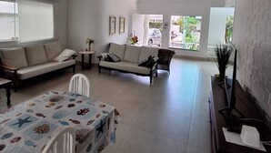 Un salon spacieux comprenant un canapé, une table à manger avec des chaises et un téléviseur posé sur un meuble.