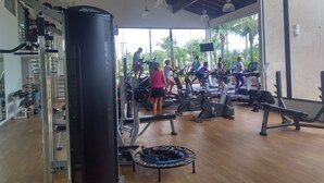 Une salle de sport équipée de machines de cardio, de matériel de musculation et d’un sac de frappe.