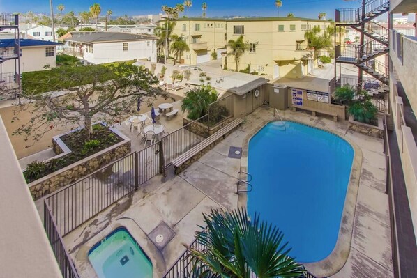 Zona residencial con piscina, mobiliario exterior y vistas a edificios vecinos.