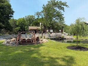 A rustic cabin with a stone wall and a wooden swing set in a park setting. - Charming Colonial w/Stream Access Pet Friendly (Tannersville)