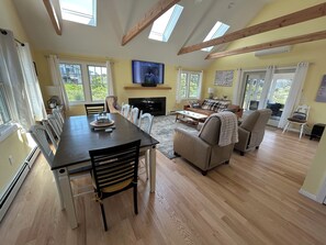 Uma sala de estar espaçosa com uma grande mesa de jantar, assentos confortáveis, lareira e claraboias.