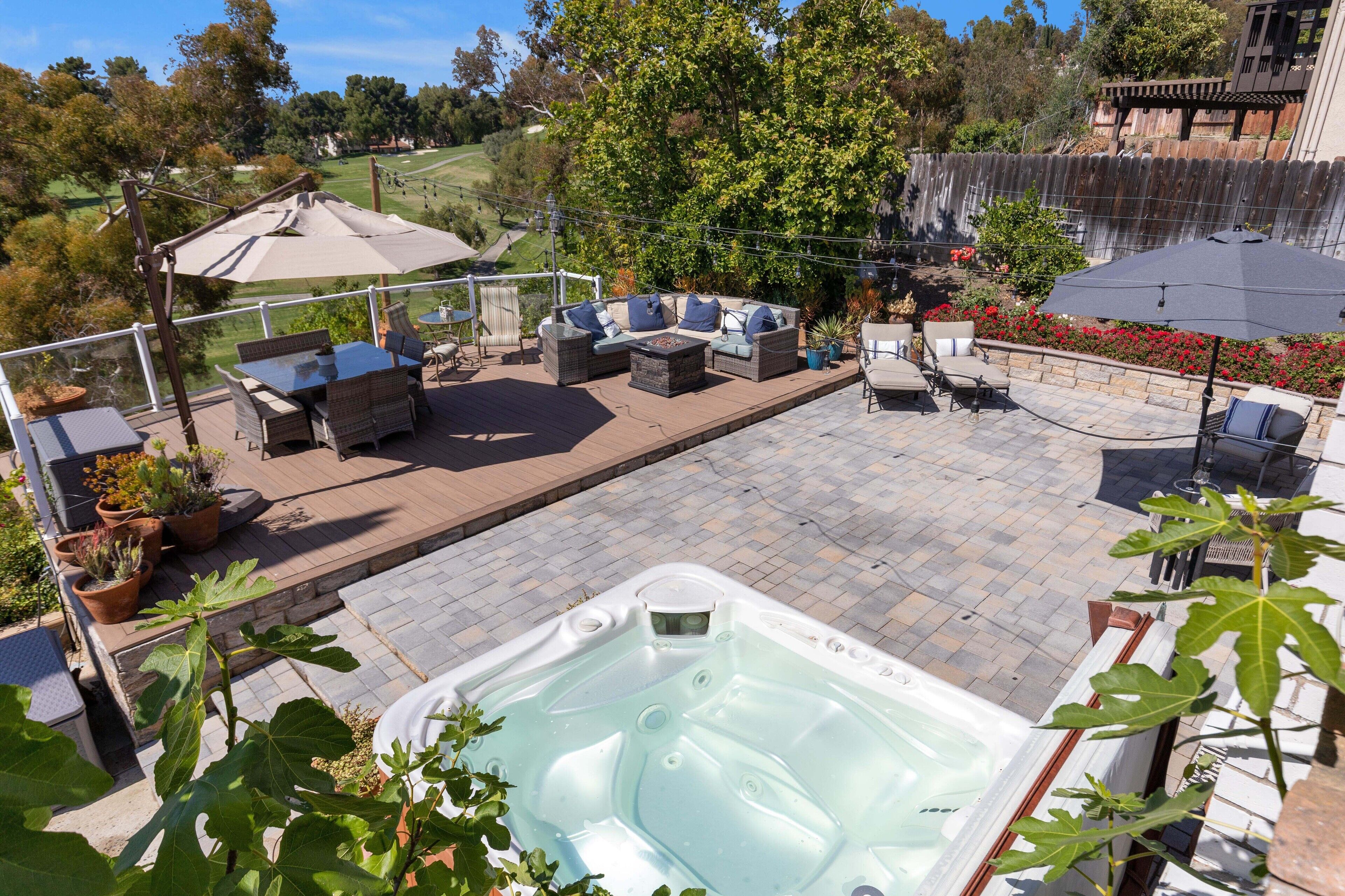 A patio area with outdoor furniture, a hot tub, and a view of a golf course.