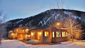 A two-story house with a covered porch and a snow-covered landscape. - Spacious Home - Hot Tub, Game Room, 2 Kitchens, 3 Living Rooms - Perfect For Large Families (Ketchum)