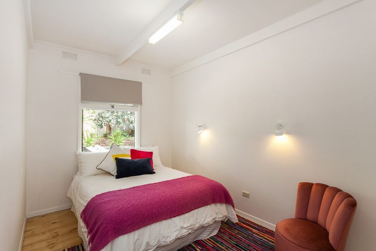 Une chambre à coucher avec un lit, une fenêtre, une chaise et un luminaire.