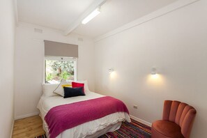 Une chambre à coucher avec un lit, une fenêtre, une chaise et un luminaire.