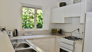 A compact kitchen with a sink, toaster, microwave, and stove.