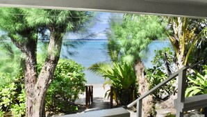 A view of a beach with a staircase leading to a sandy area, surrounded by trees and vegetation.