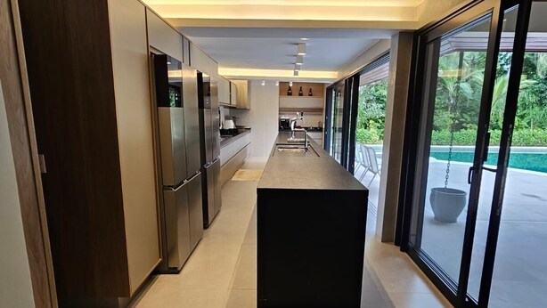 A modern kitchen with a central island, built-in appliances, and large windows offering a view of the outdoors.