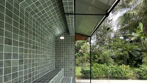 A tiled indoor pool area with a view of lush greenery outside.