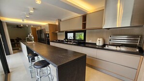 A modern kitchen with a central island, bar stools, a built-in oven, and a large window.