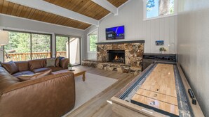 Un amplio salón con chimenea de piedra, un ventanal grande y una mesa de billar.