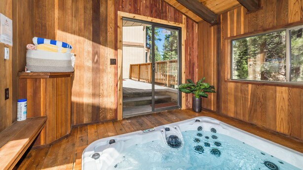 Una cabaña de madera con jacuzzi, paredes de madera, un banco y una planta en maceta.