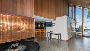 Un vestíbulo moderno con paneles de madera, mostrador de recepción, zona de estar y un amplio ventanal que proporciona luz natural.