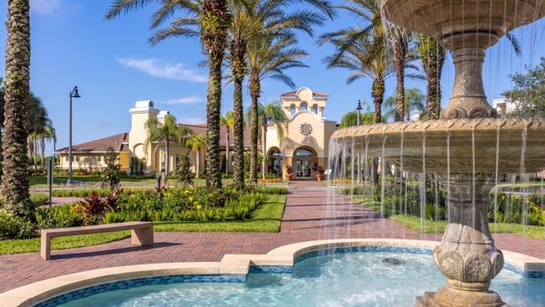 A fountain with water jets, surrounded by a pool and palm trees. - Vista Cay Lakeview 3BR + Den,  Near OCCC, I-Drive, Universal & Epic Universe, (Orlando)