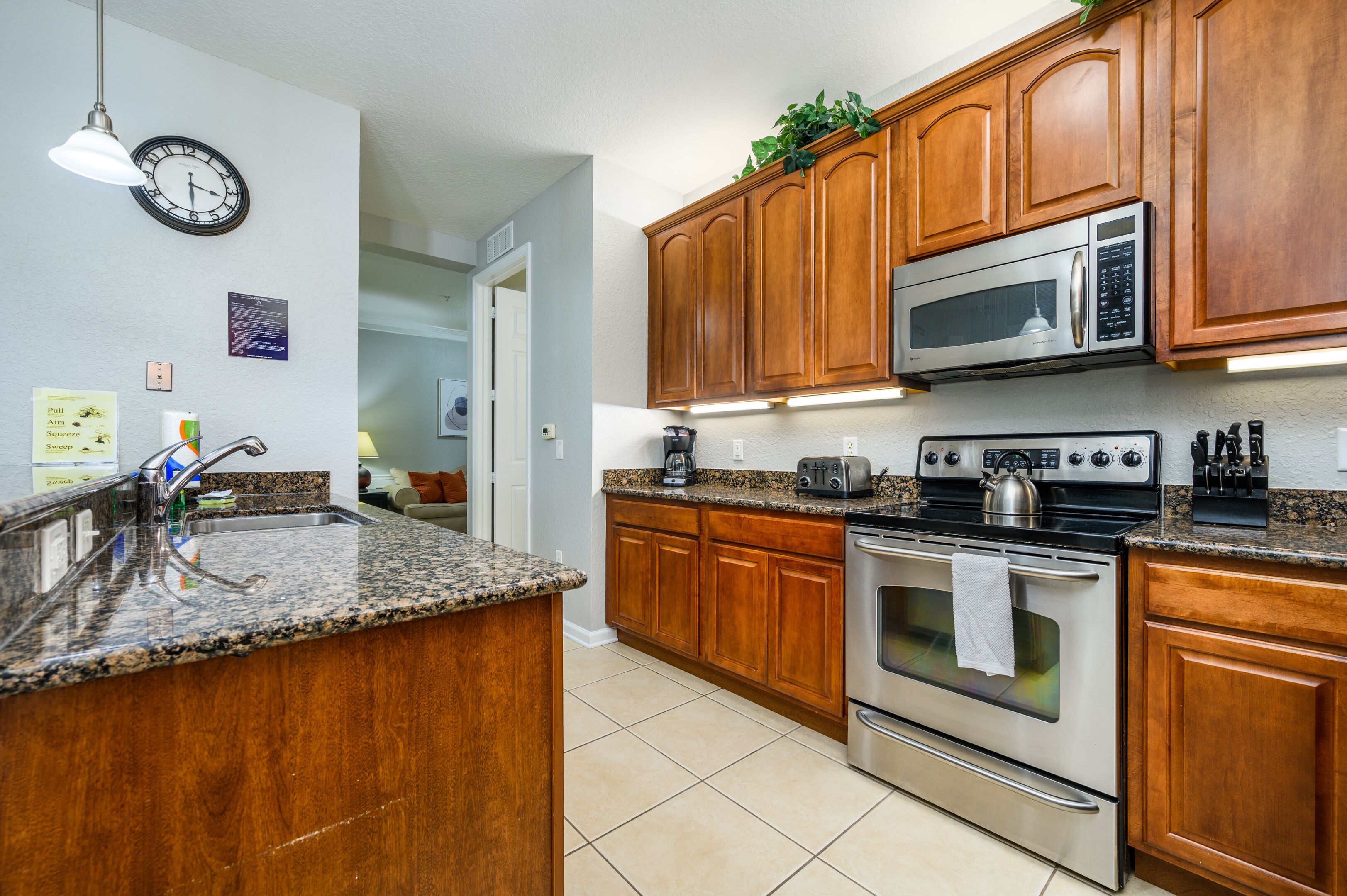 A kitchen with wooden cabinets, a stainless steel oven, a microwave, and granite countertops.
