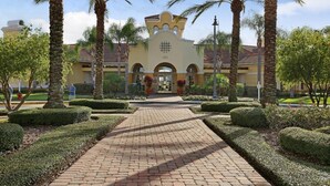 A building with a yellow facade, arched entrance, and palm trees. - Vista Cay Lakeview 3BR + Den,  Near OCCC, I-Drive, Universal & Epic Universe, (Orlando)
