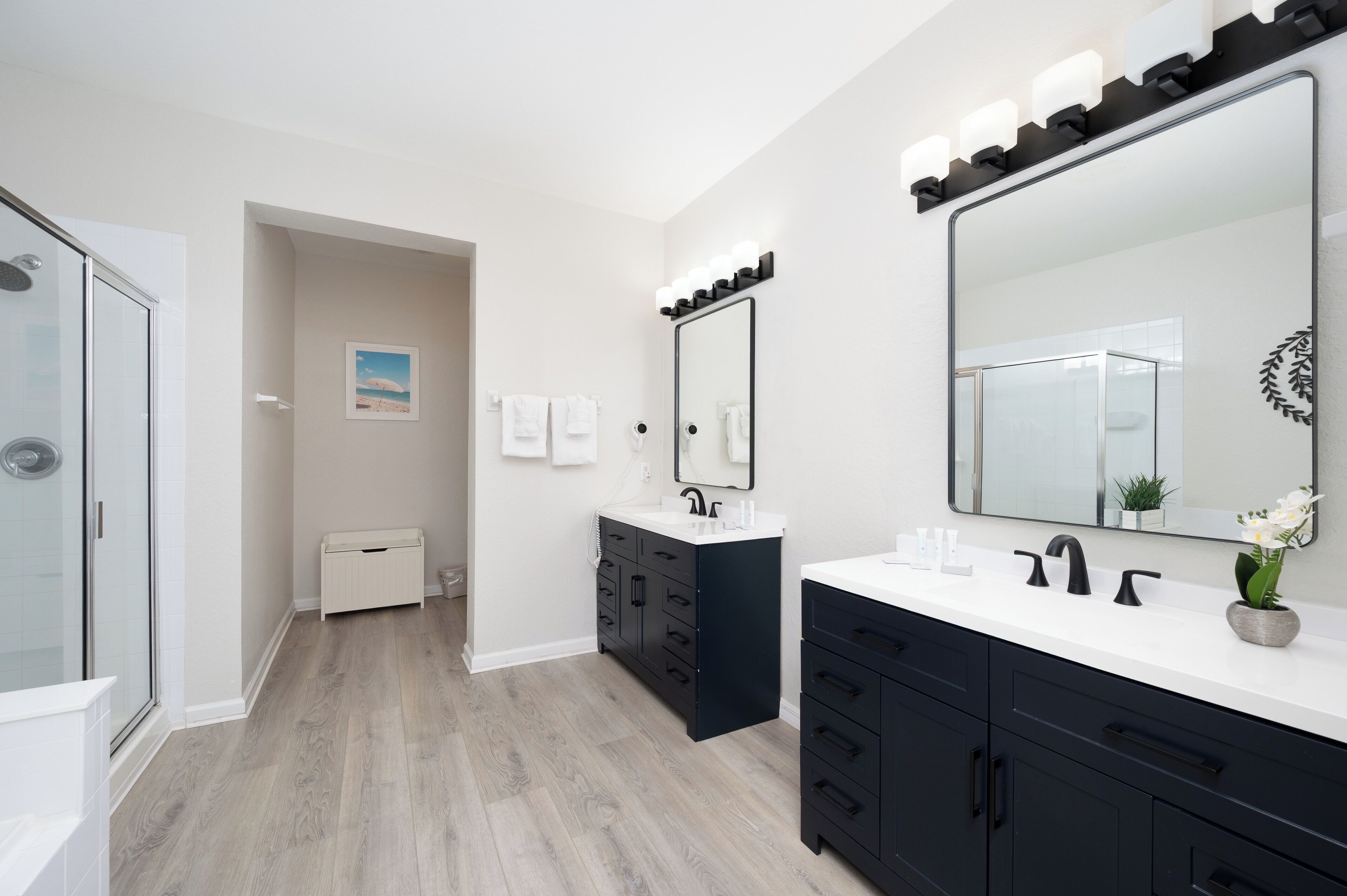 A modern bathroom with two sinks, a large mirror, and a walk-in shower.