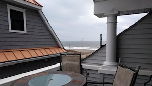Een balkon met een tafel en stoelen, met uitzicht op een strand.
